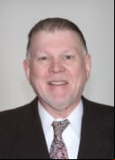 Commissioner Tom Winters wearing black blazer and paisley tie.